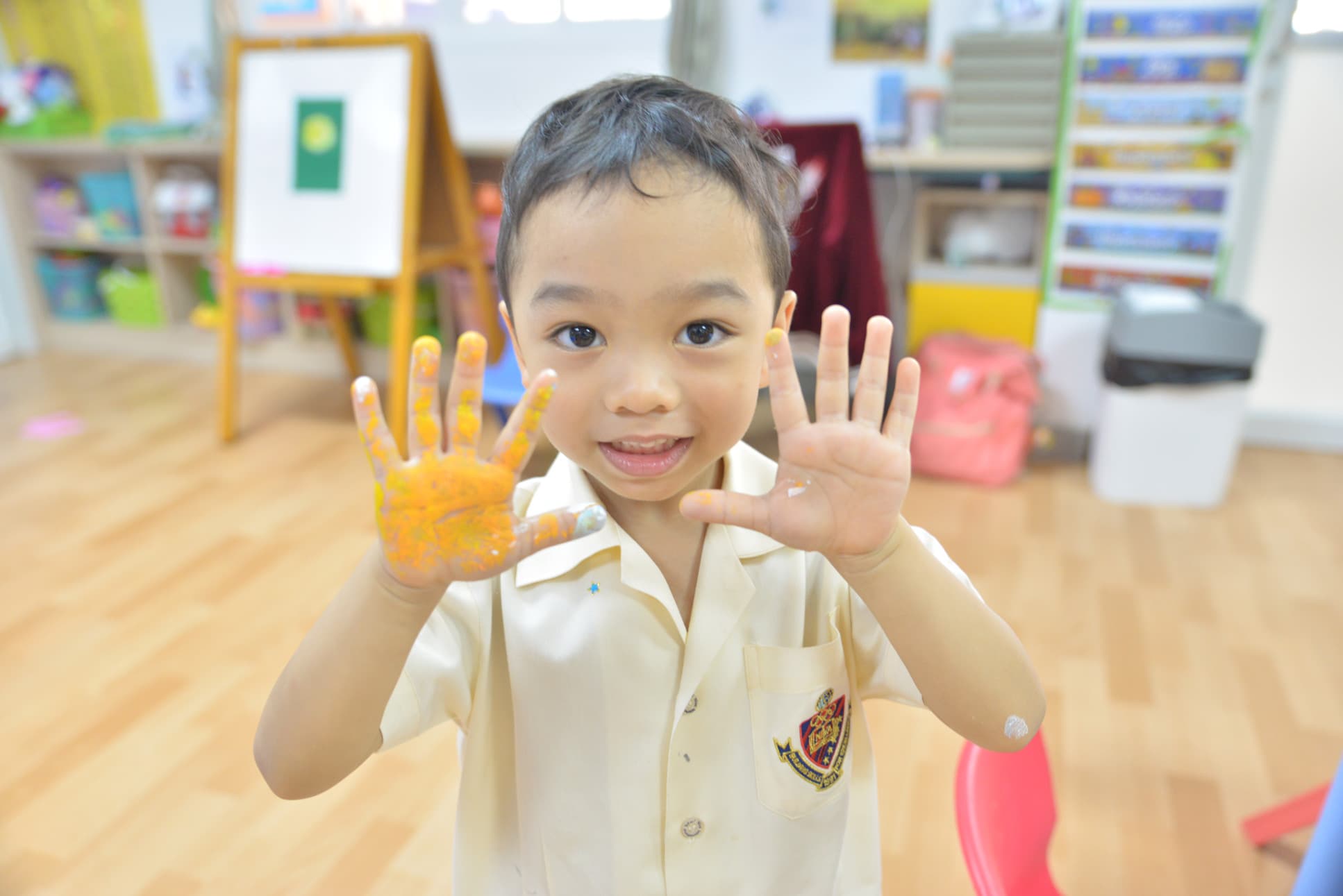 NIVA Kindergarten student showing his painted hands from a class activity