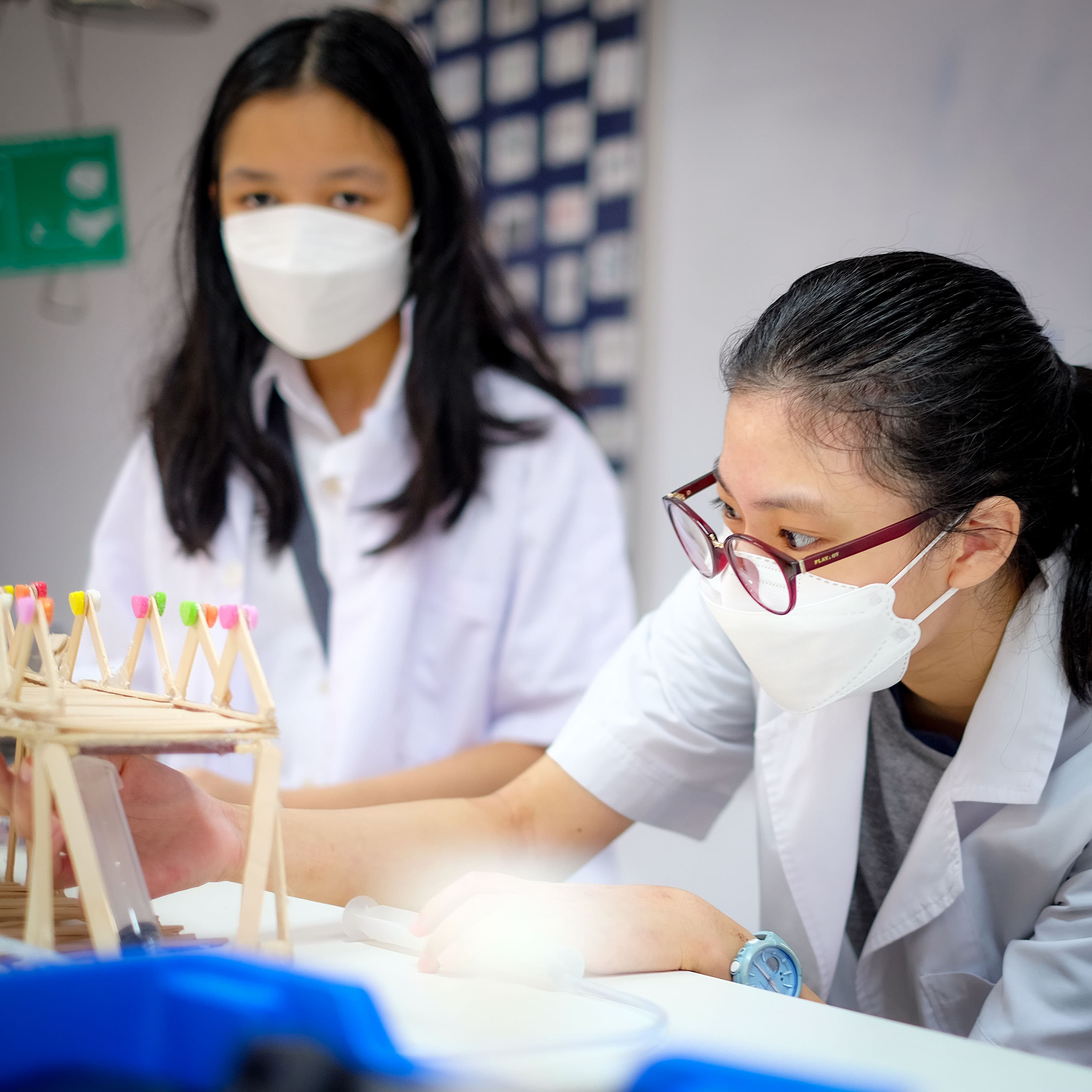 A middle school student at NIVA building a wooden mini bridge as part of her science class