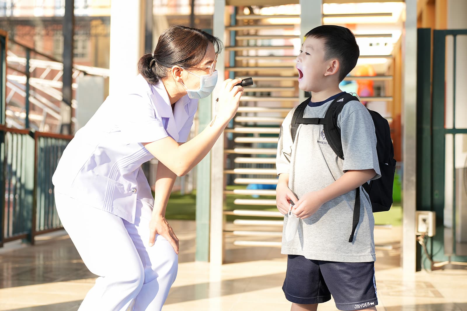 A NIVA American International School kindergarten student greets teachers and TAs in the morning.