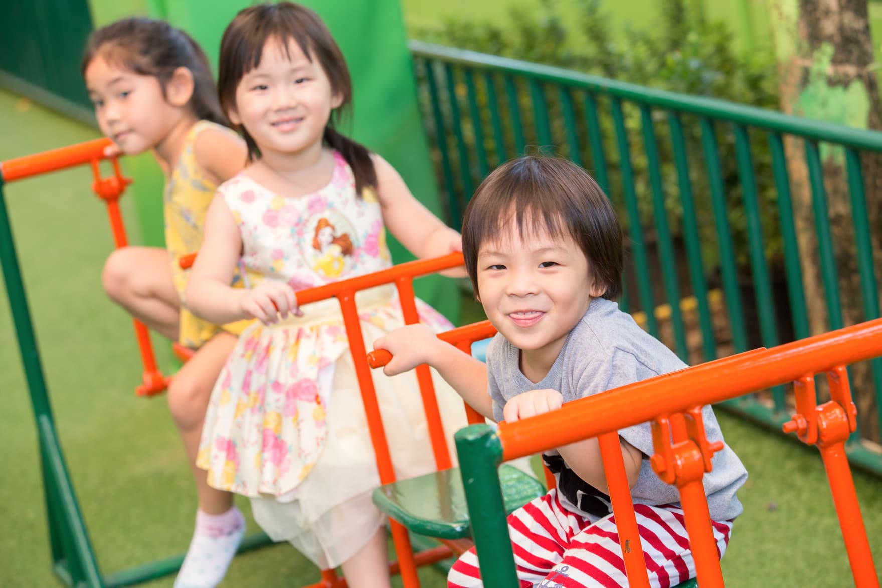 Nursery kids sitting on playground, smiling at camera