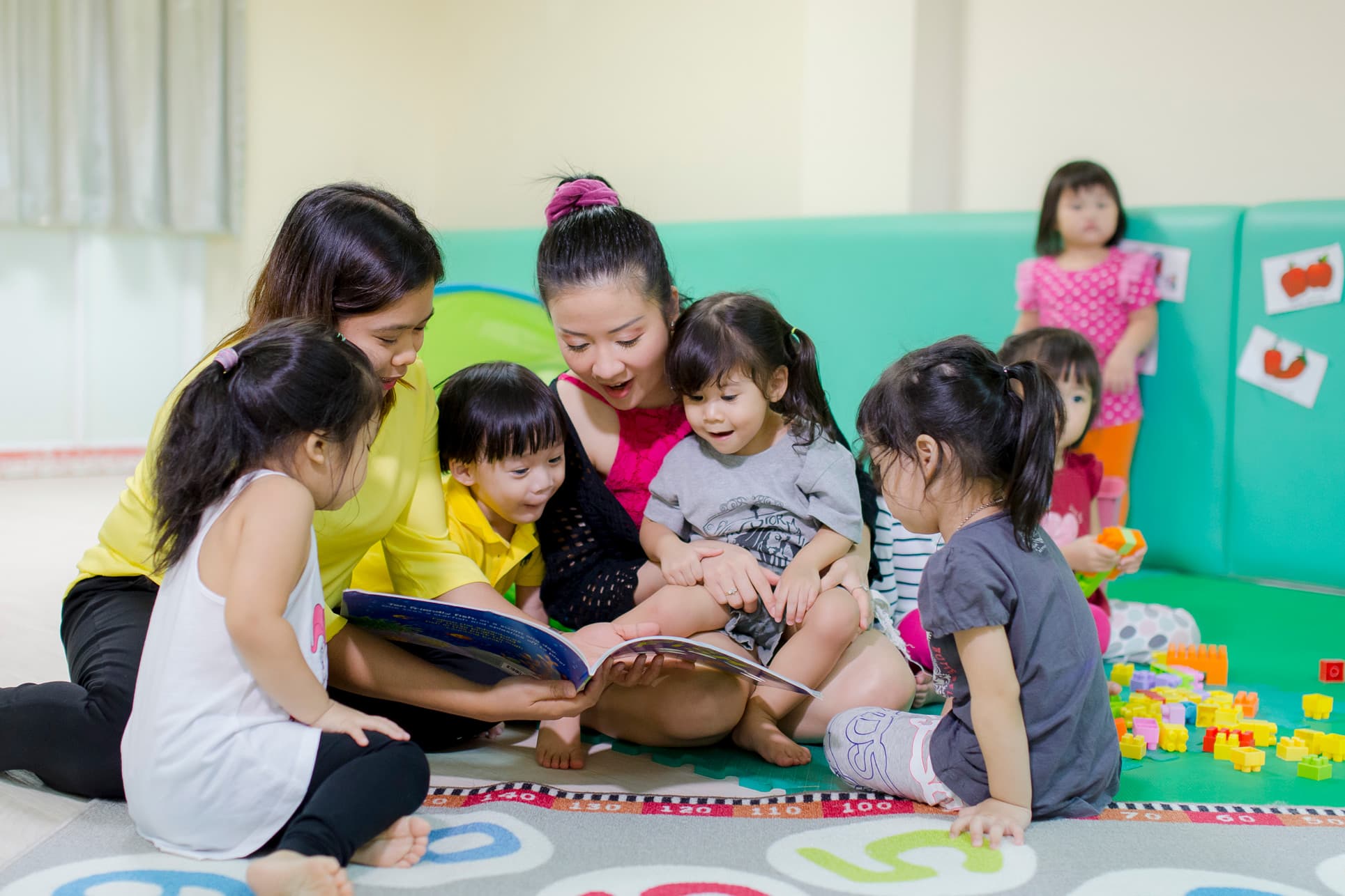 Nursery teachers and students reading together