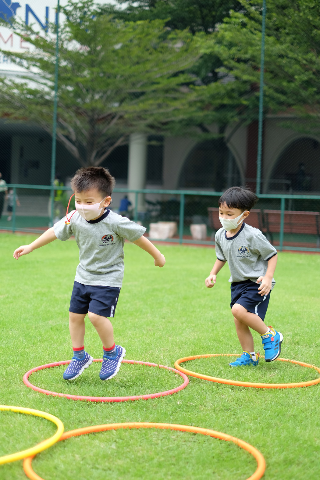 Two children jumping into hoops on the grass