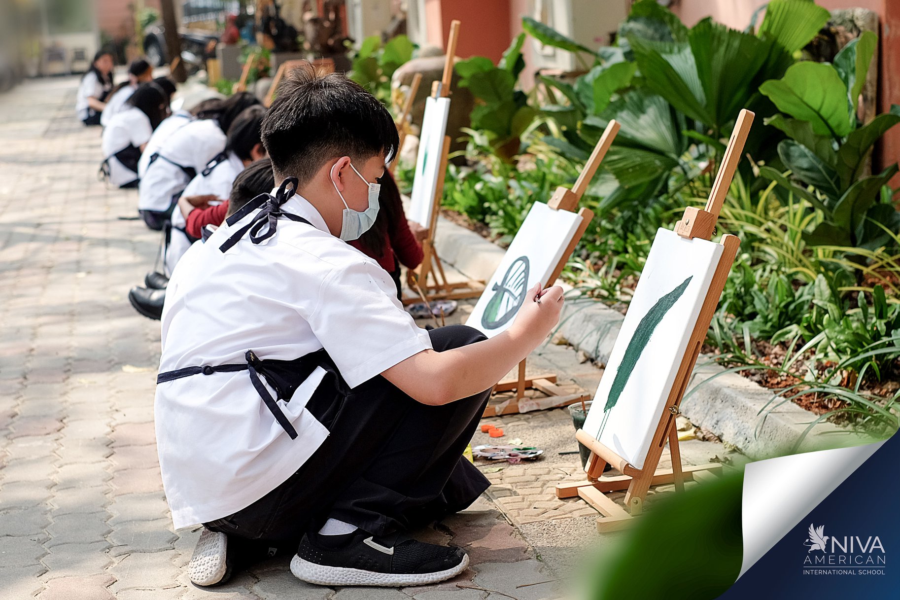Students painting leaves beside the patio garden