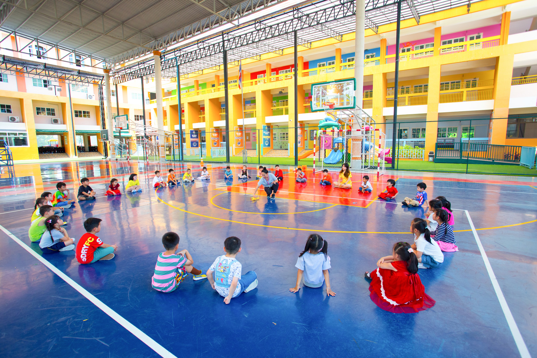 Kindergarten students sitting with hoops during PE on the court