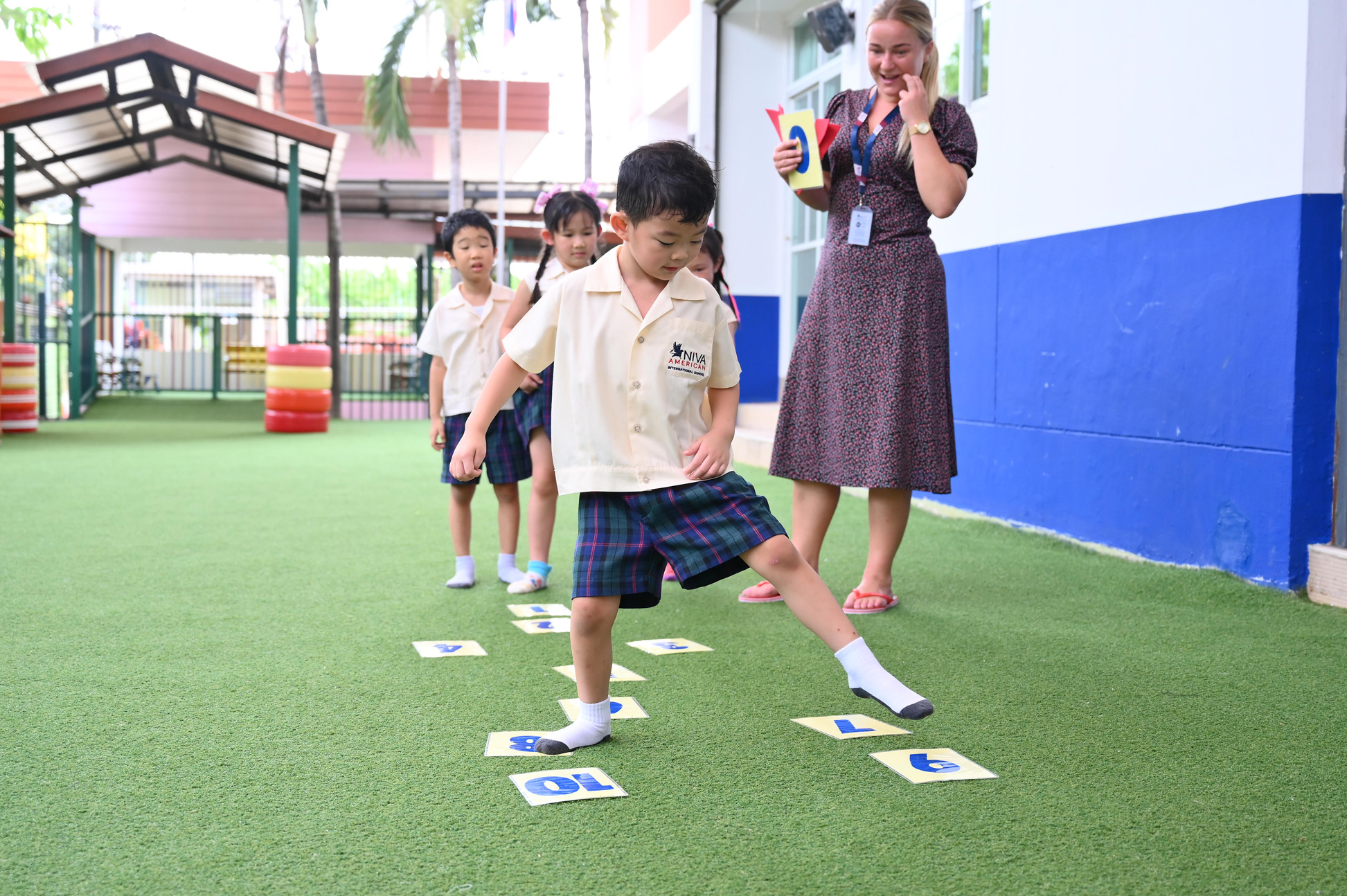 Kindergarten students using number cards in an outdoor maths activity