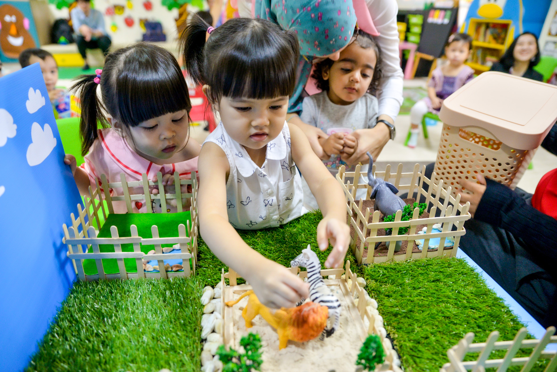 Nursery children playing with toy farm animals