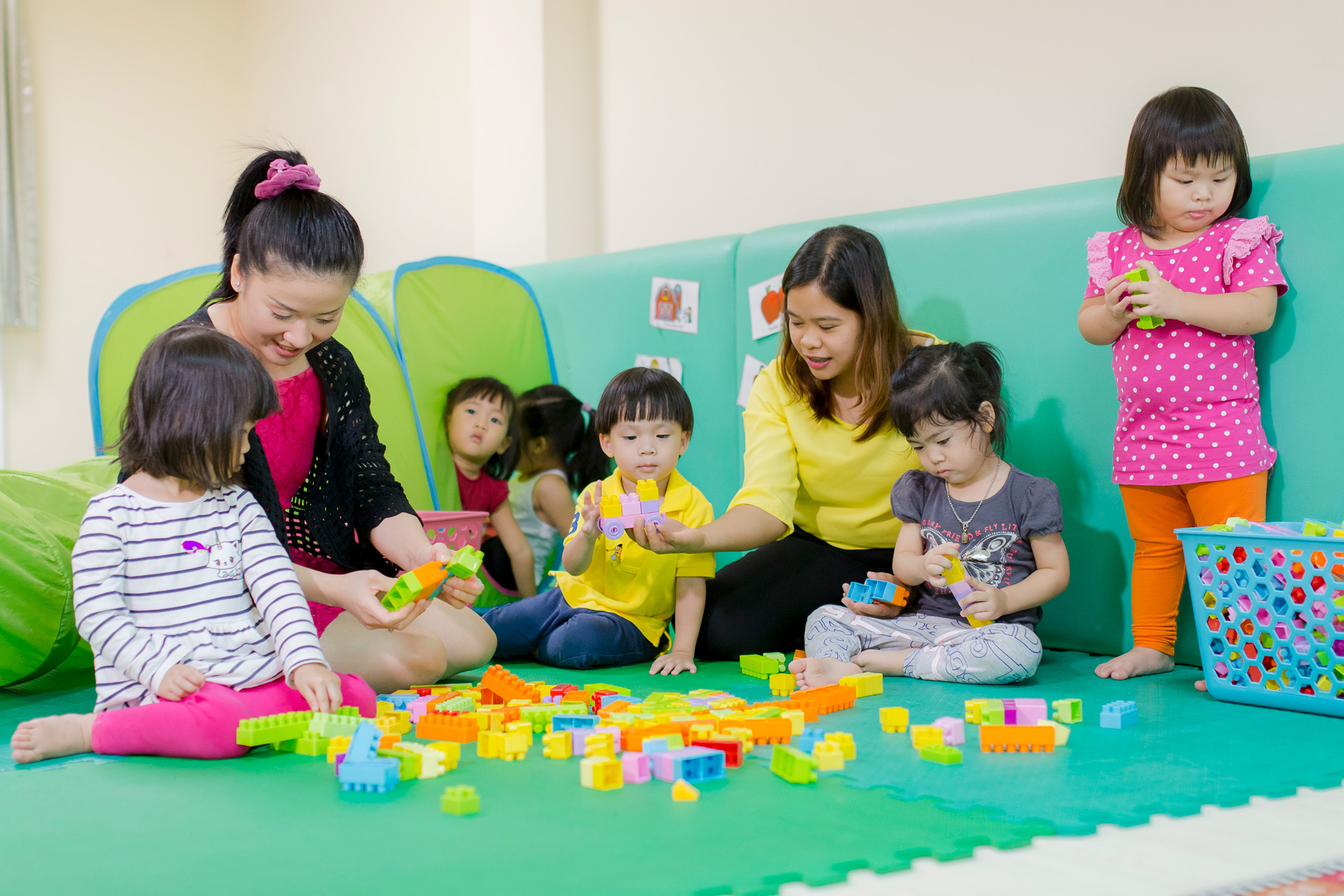 Nursery teachers and children playing with building blocks