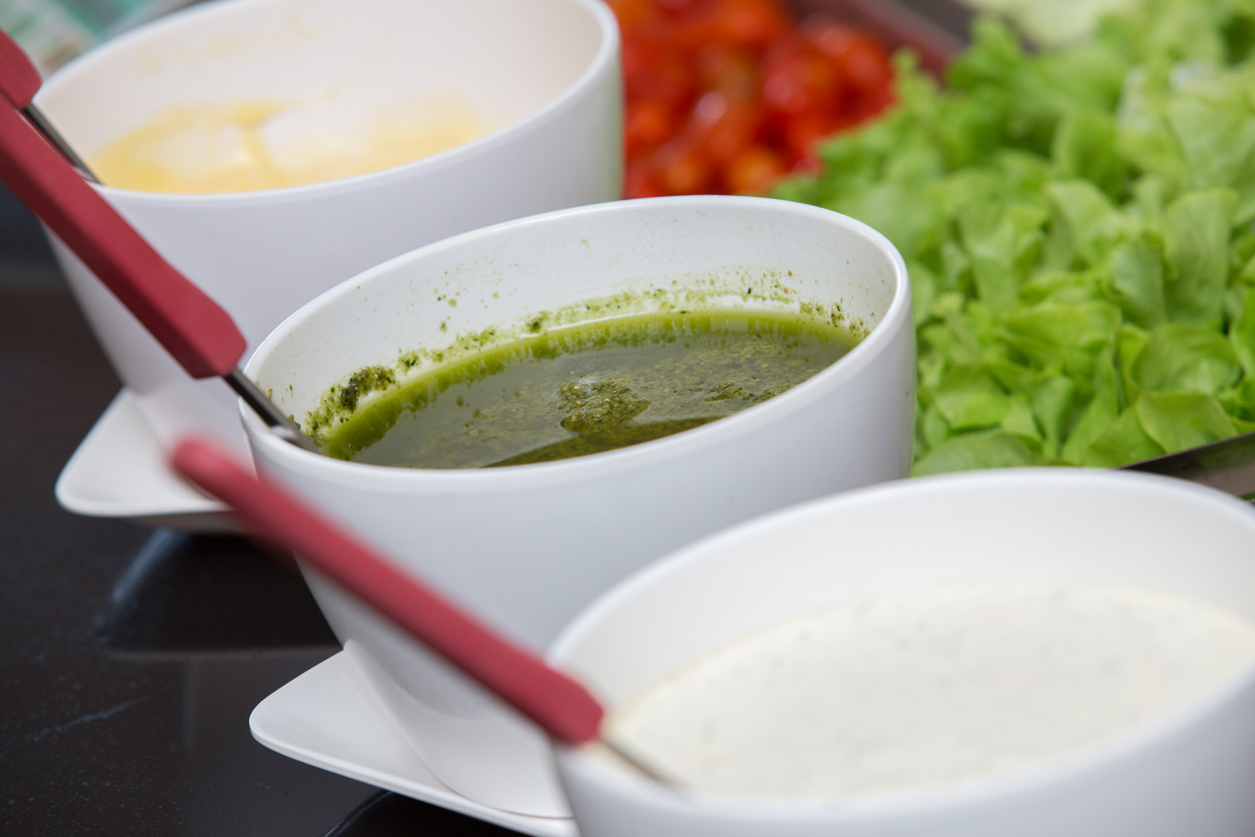 Bowls of sauces beside lettuce at the canteen counter