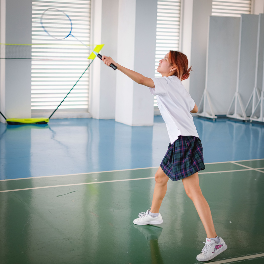 Student reaching up to hit a shuttlecock