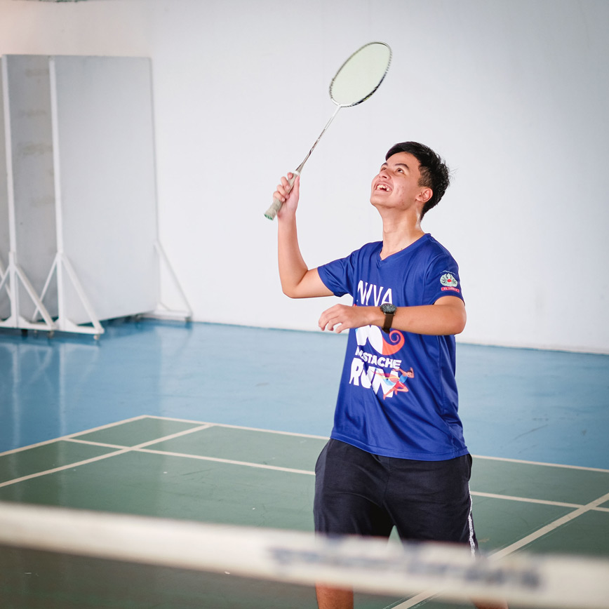 Student watching a shuttlecock with racket raised