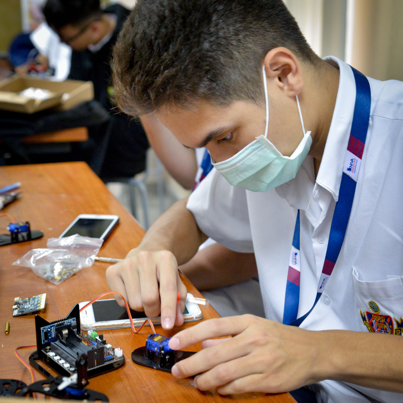Student assembling a robot at a classroom desk