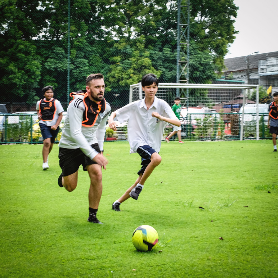 Students chasing a football across the field
