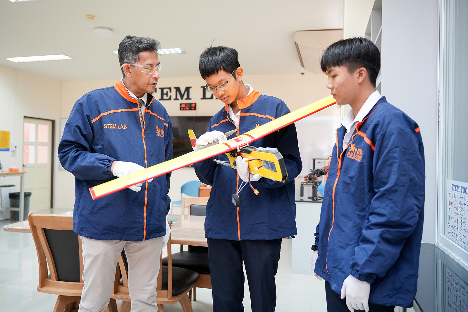 Teacher and students examining a model airplane