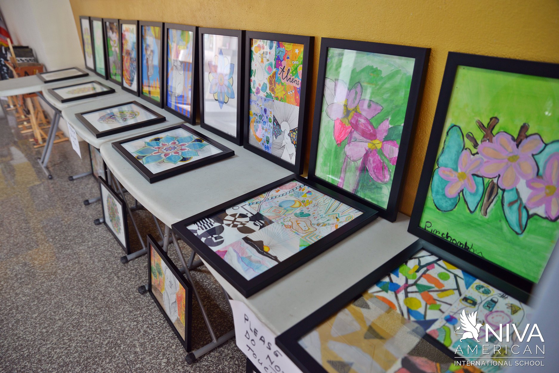 Student paintings displayed on tables and easels