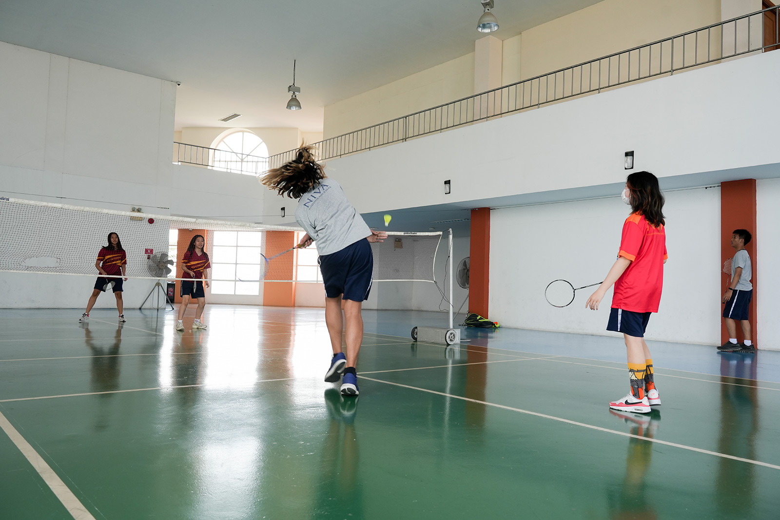 Student jumping to hit a shuttlecock during badminton