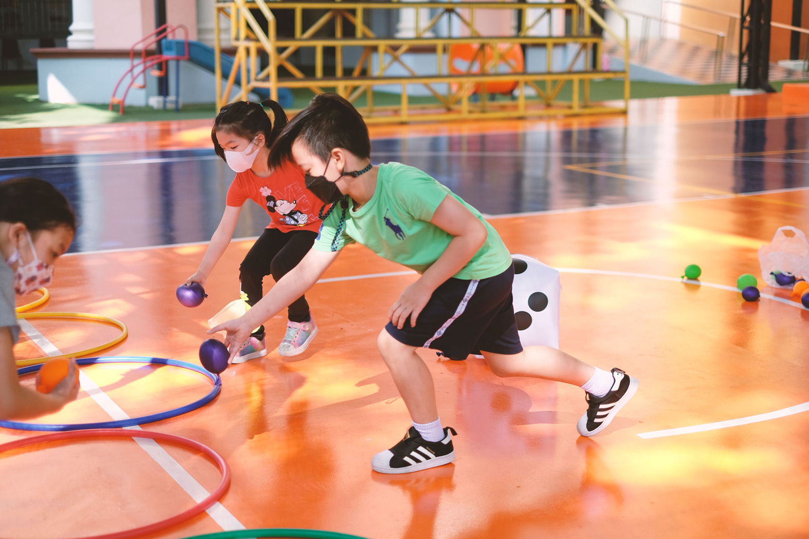 Children playing a game with hoops and colored balls on the court
