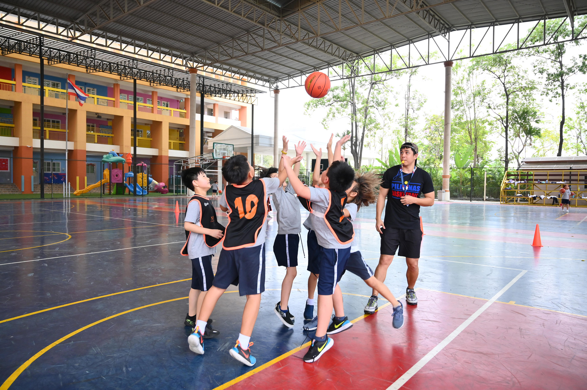 Students reaching for a basketball during a game