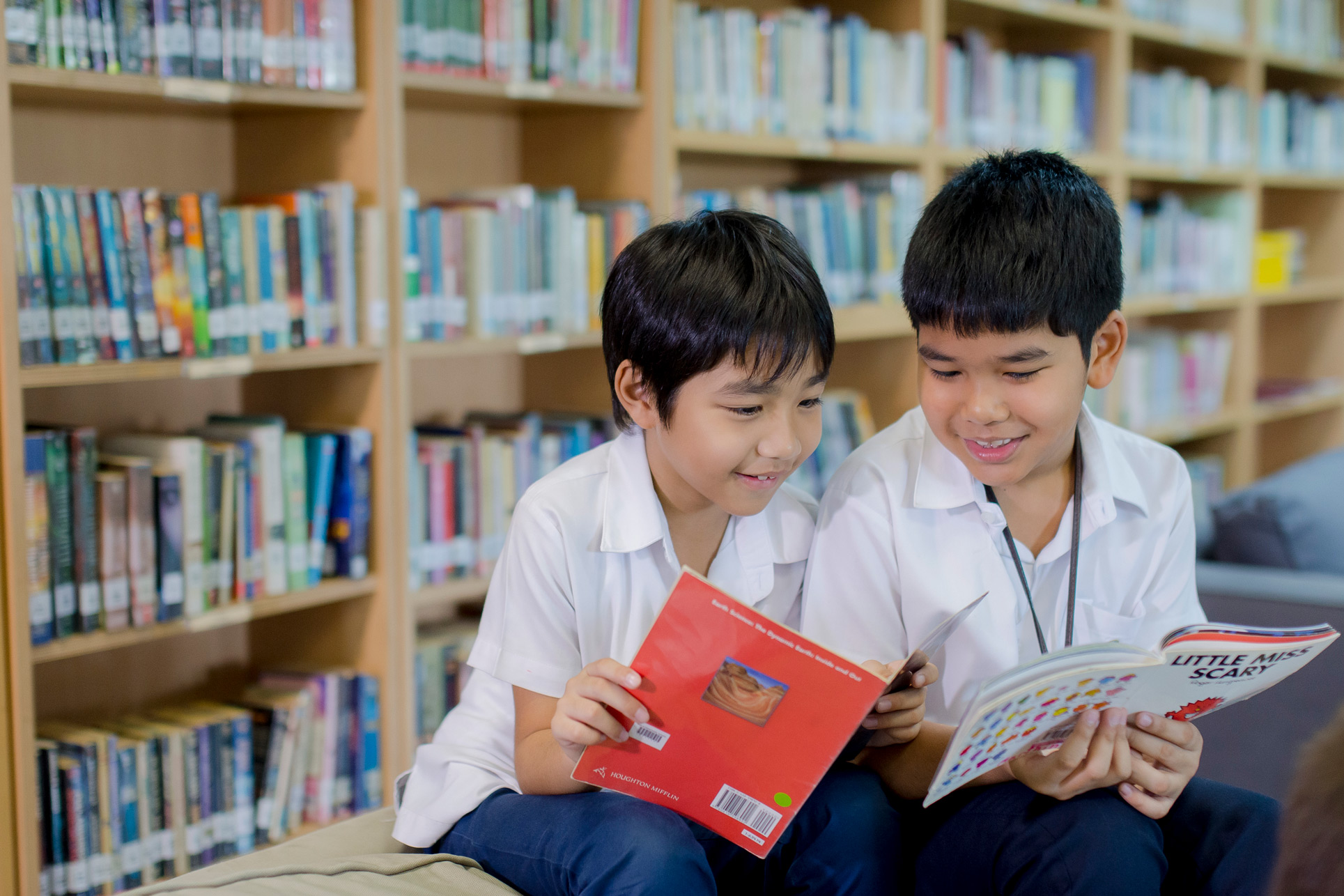 Two boys reading books in the library