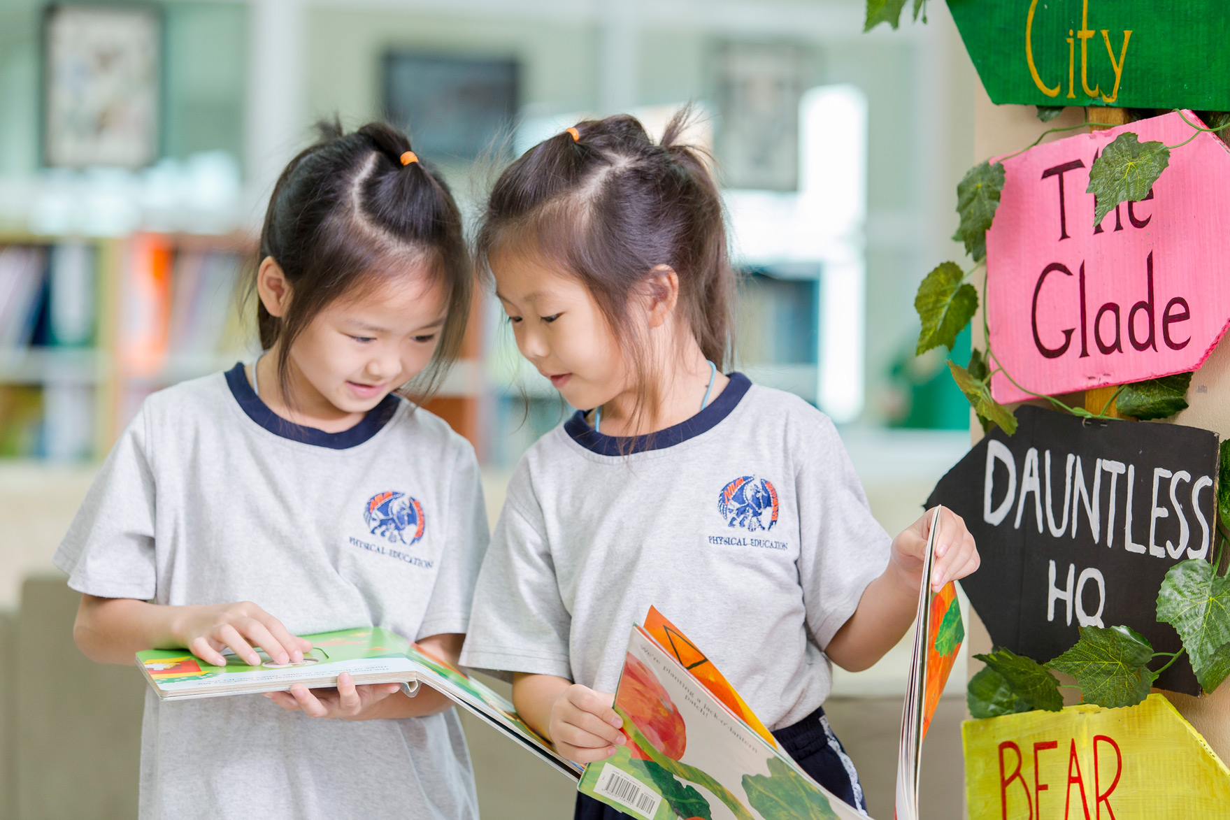 Two girls reading a book together in the library