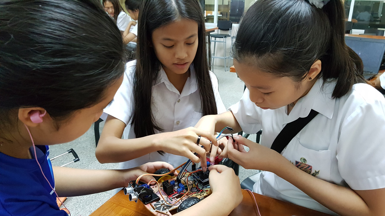 Three students assembling a robot together